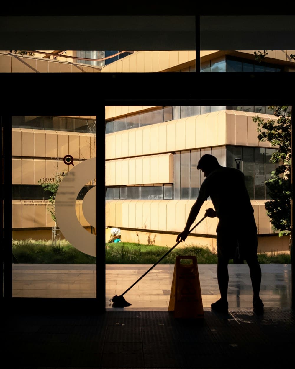 Cleaner washing office windows at dusk