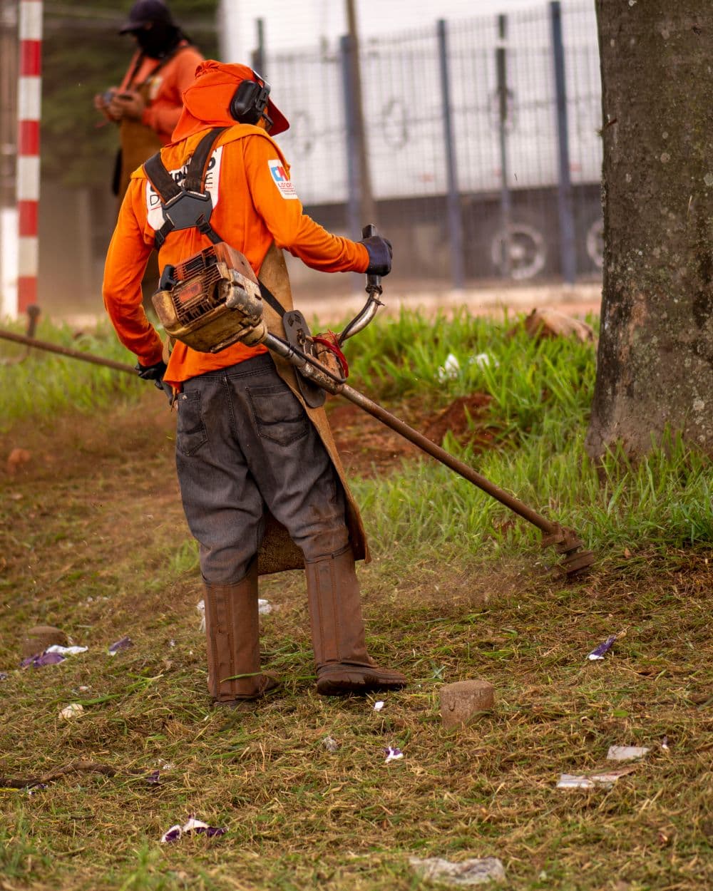 Landscaper in safety gear running a string trimmer