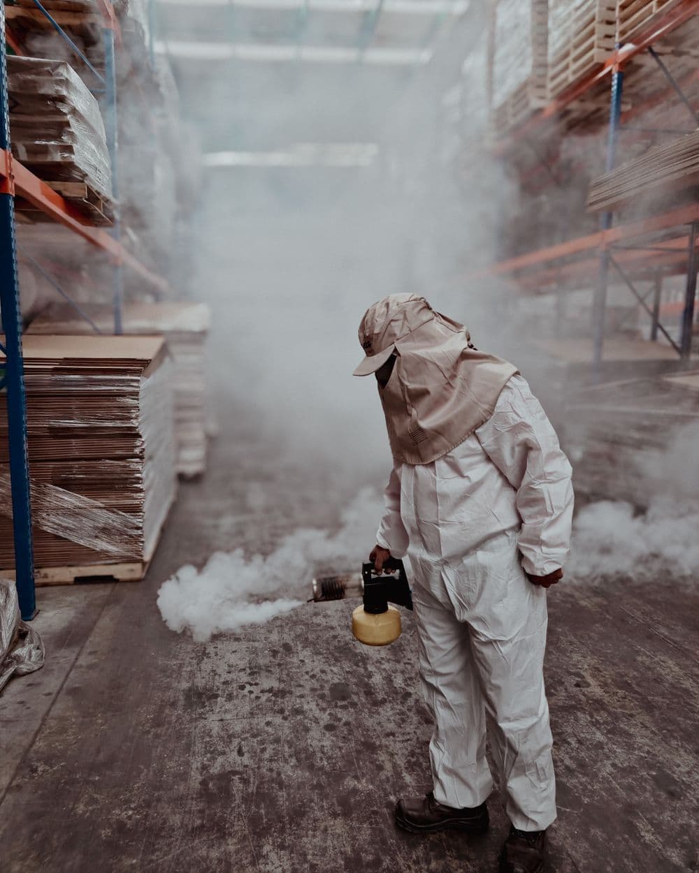 Exterminator in protective gear fumigating a warehouse