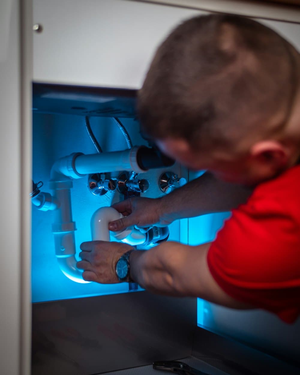 Plumber repairing pipes under a sink