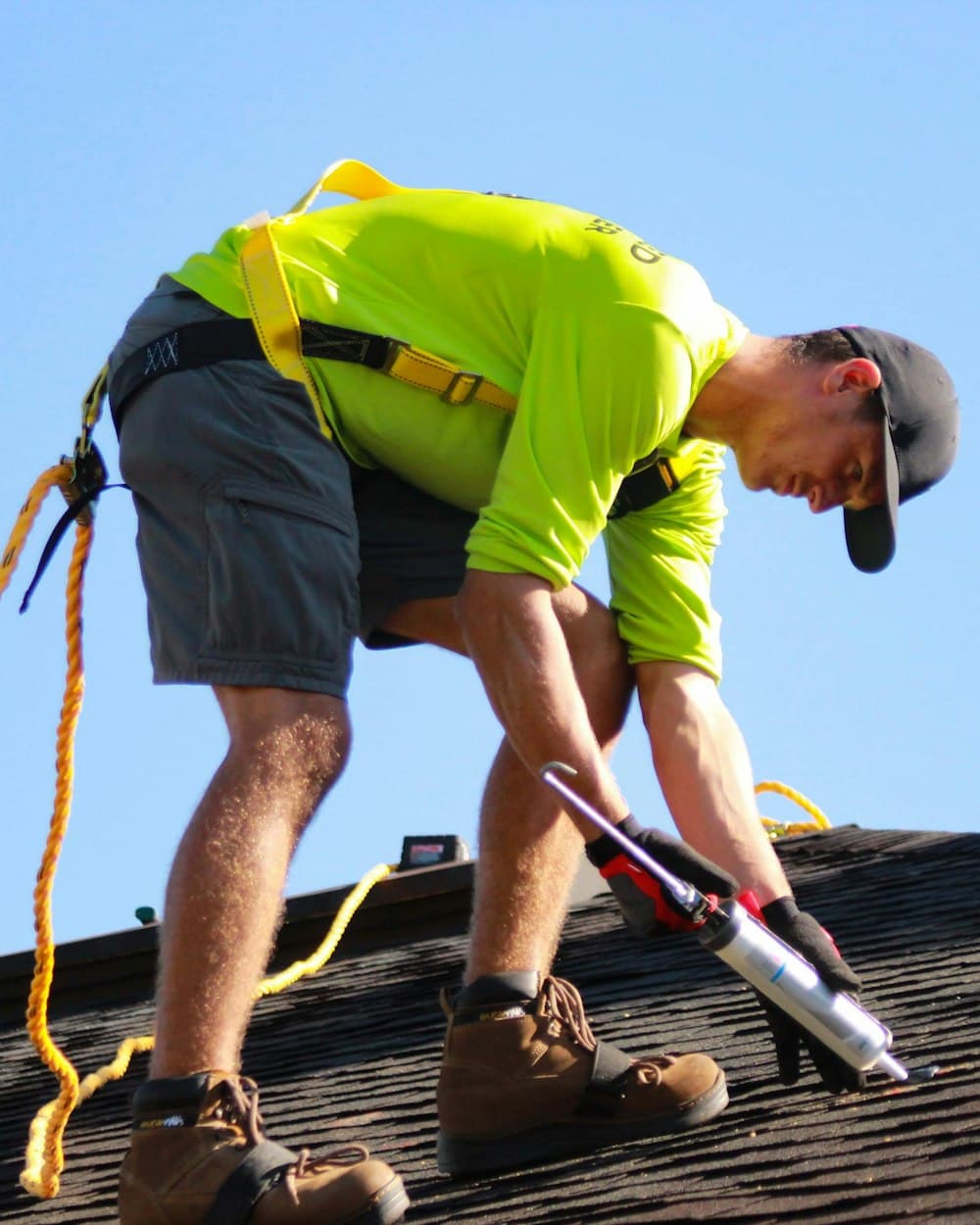Roofer installing shingles with a nail gun