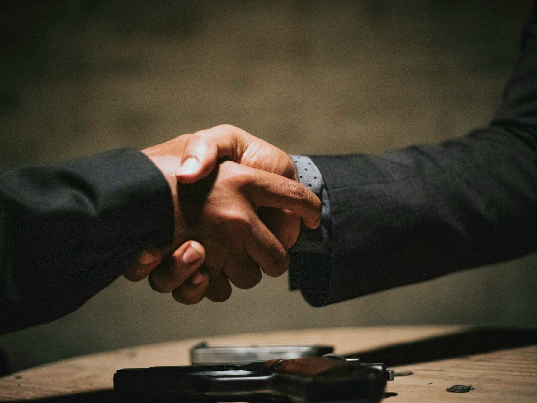 Two people shaking hands over a signed agreement